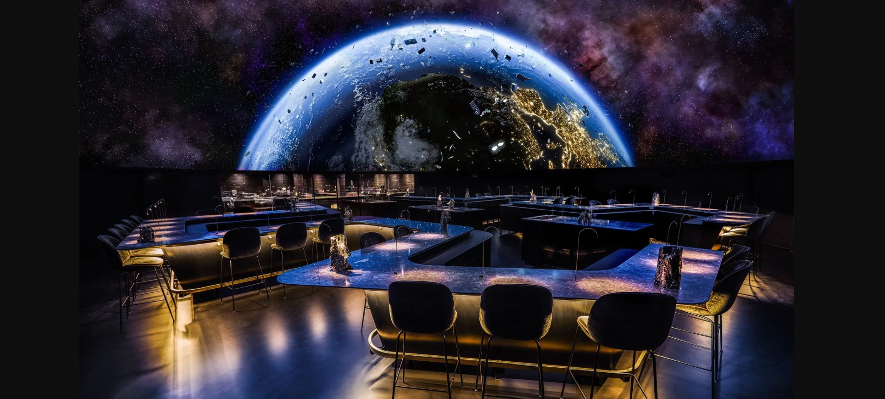 The interior of "Iris" in Norway. A dark room where the seating is viewing a giant globe.