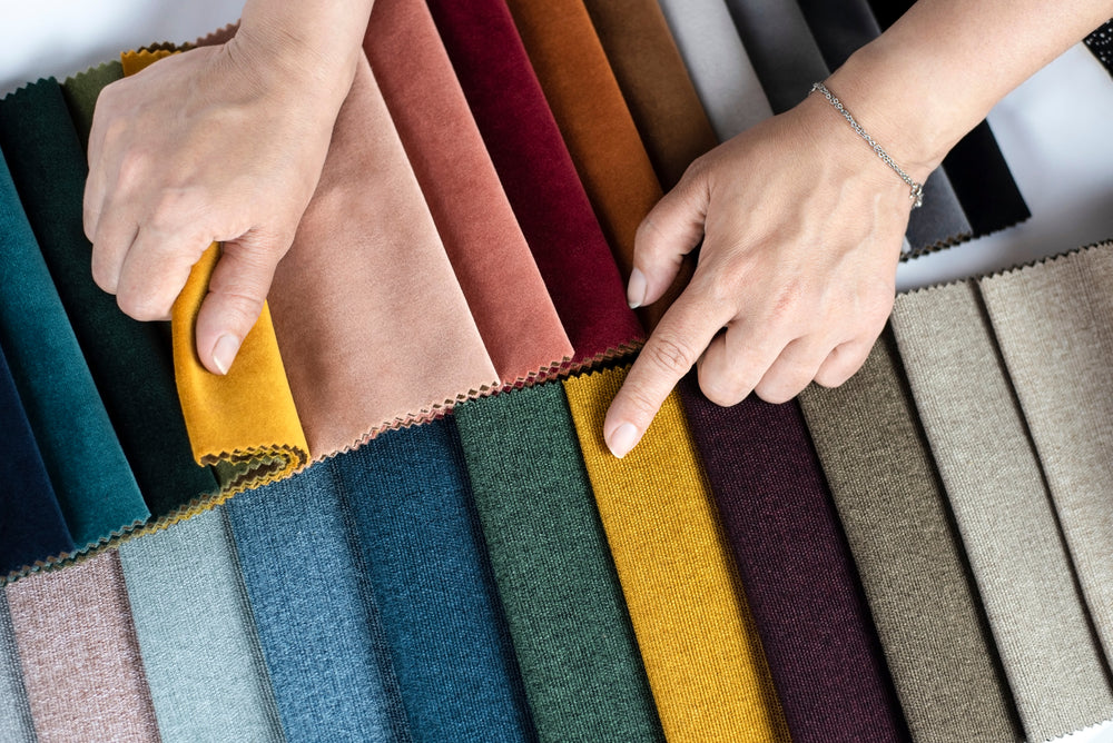 A hand browses through memo books of fabrics.