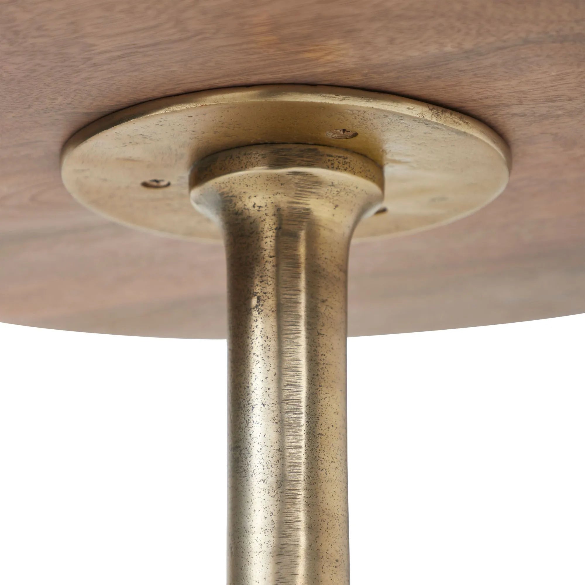 Close-up view of the underside of the Sparta mango wood side table with a tulip base and antique brass base plate, highlighting the wood texture and fastening screws.